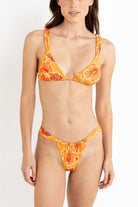 Woman wearing an orange floral bikini against a white background